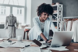 Woman standing at computer desk working on laptop.