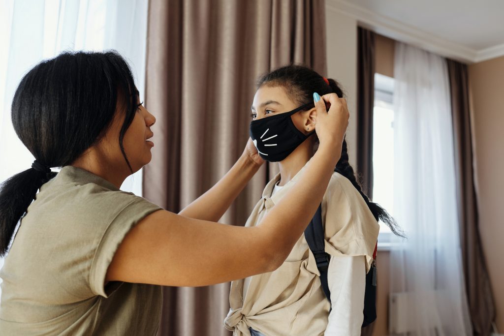 Woman putting mask on young girl.