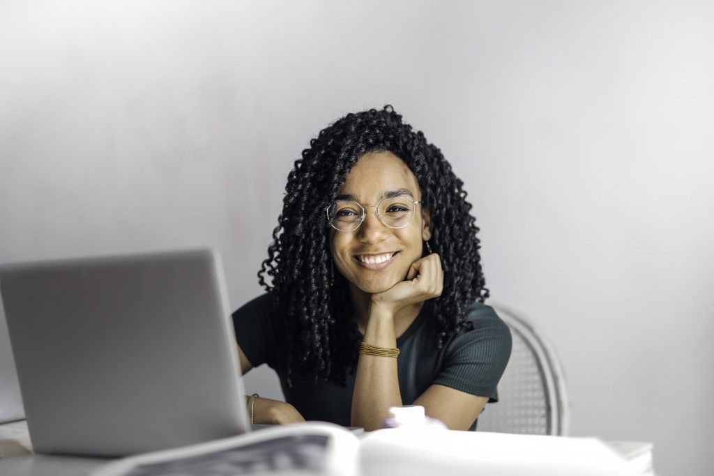 Woman at computer desk smiling at camera.